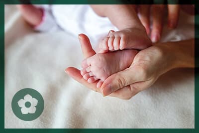 Baby feet in mother hands. Tiny Newborn Baby's feet on female Shaped hands closeup. Mom and her Child. Happy Family concept. Beautiful conceptual image of Maternity