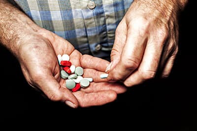 Heap of colorful medical pills in senior male hands closeup.